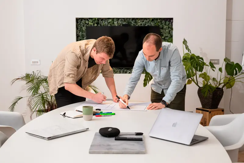 Two team members sketching a website flow together on paper.